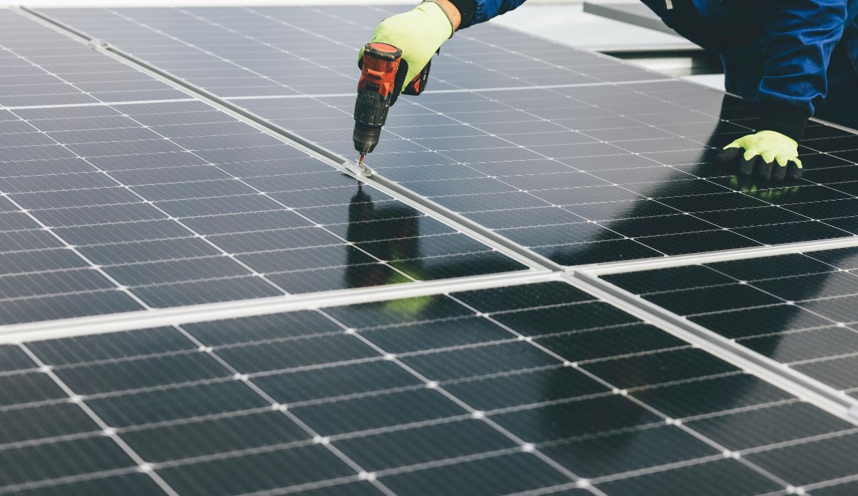 Installer drilling a mounting rail on a solar panel