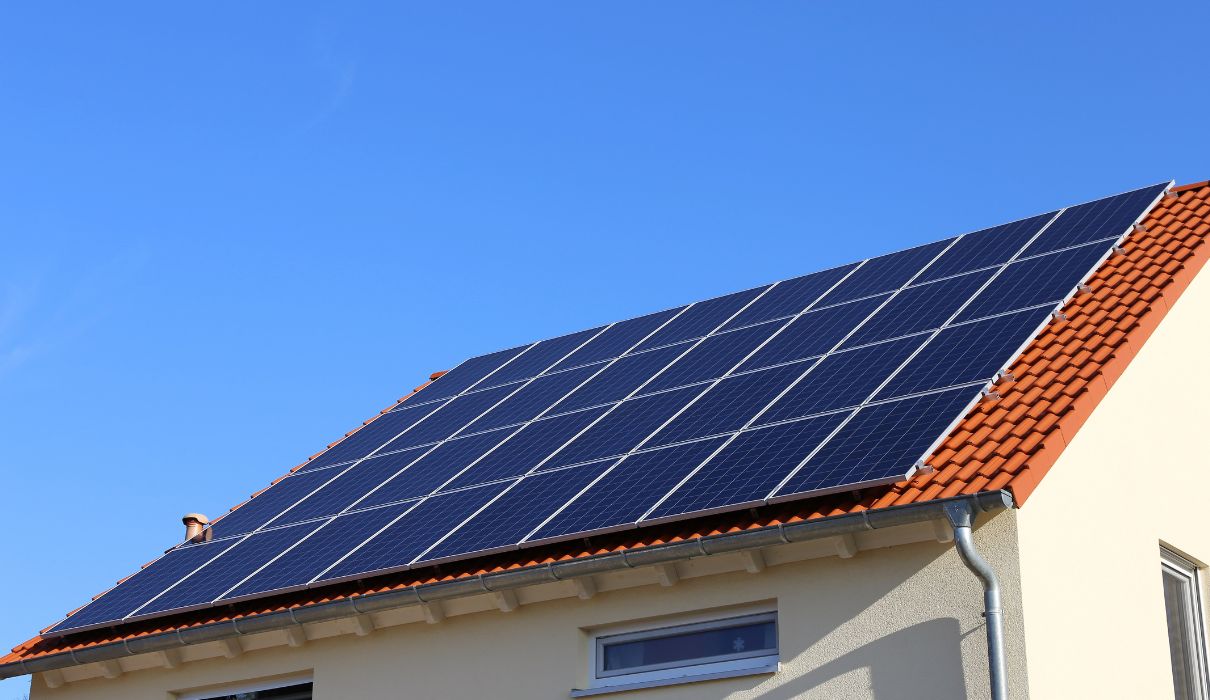 Solar panels installed neatly across a tiled pitched roof against a blue sky