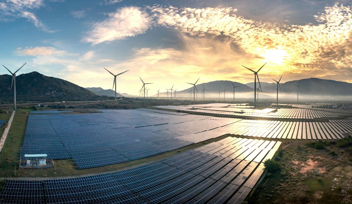 Large solar and wind farm at sunset with mountains