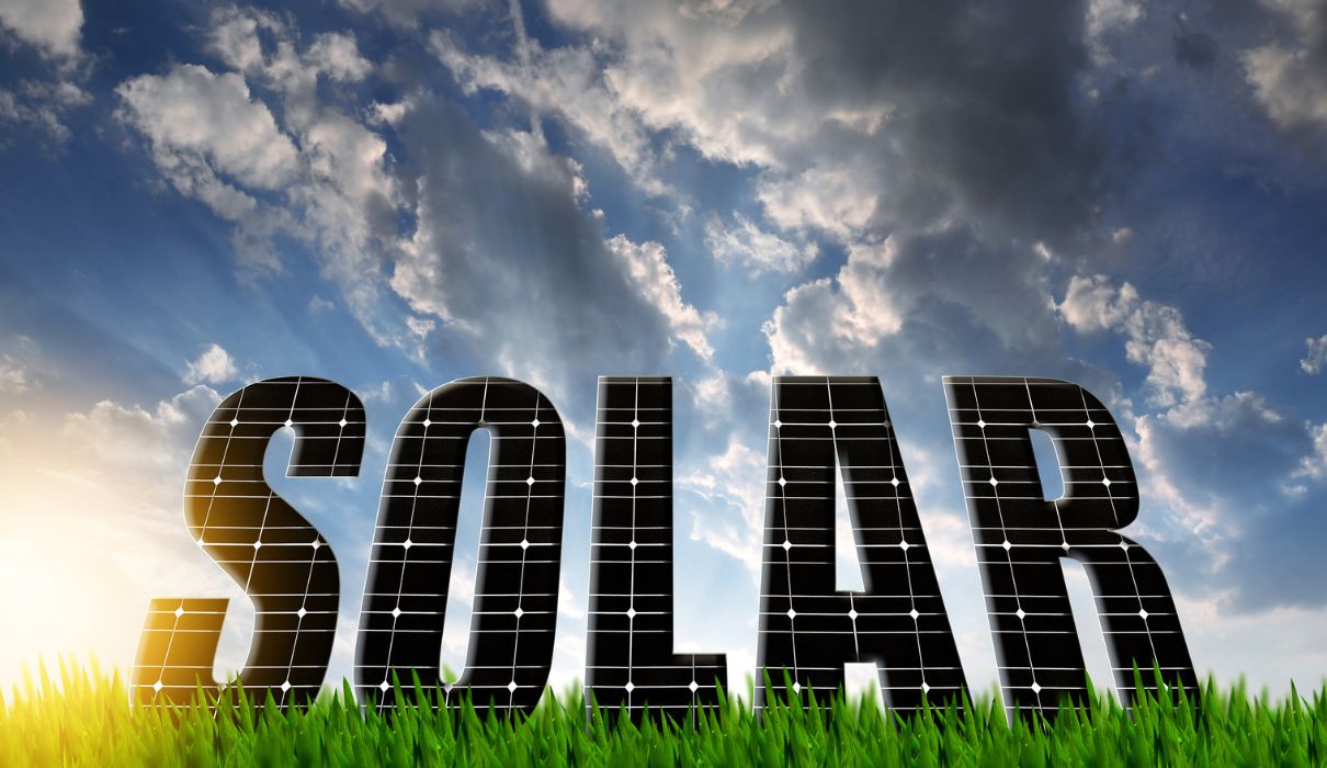 SOLAR text made of solar panels against cloudy sky